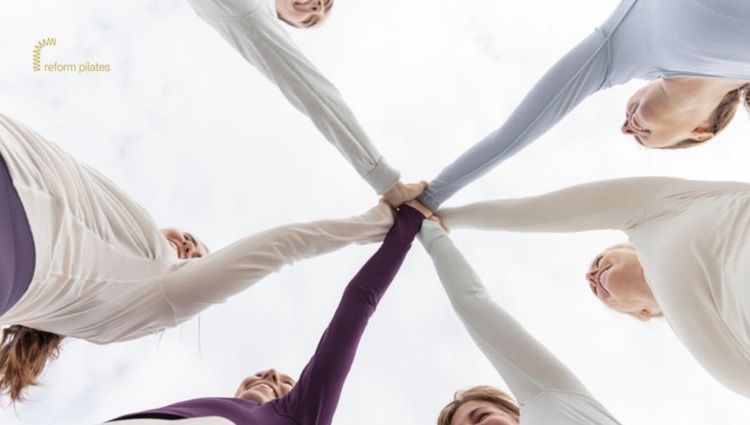 Reform Pilates class stacking hands in a circle