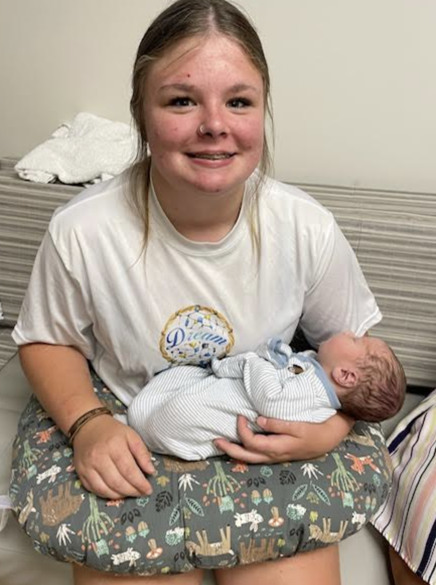 Teen girl holding her newborn baby sibling
