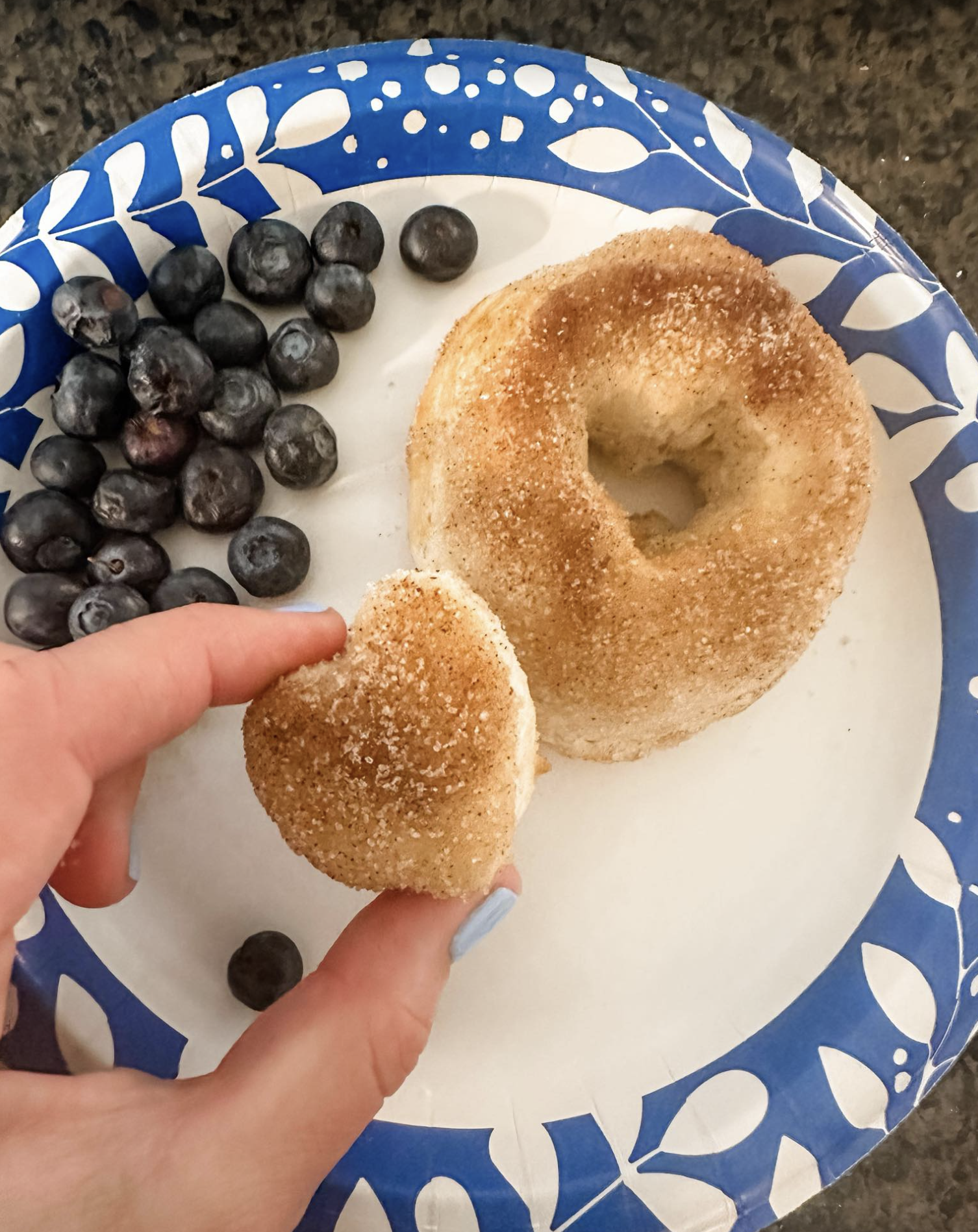 Air fryer donut held over a plate of blueberries