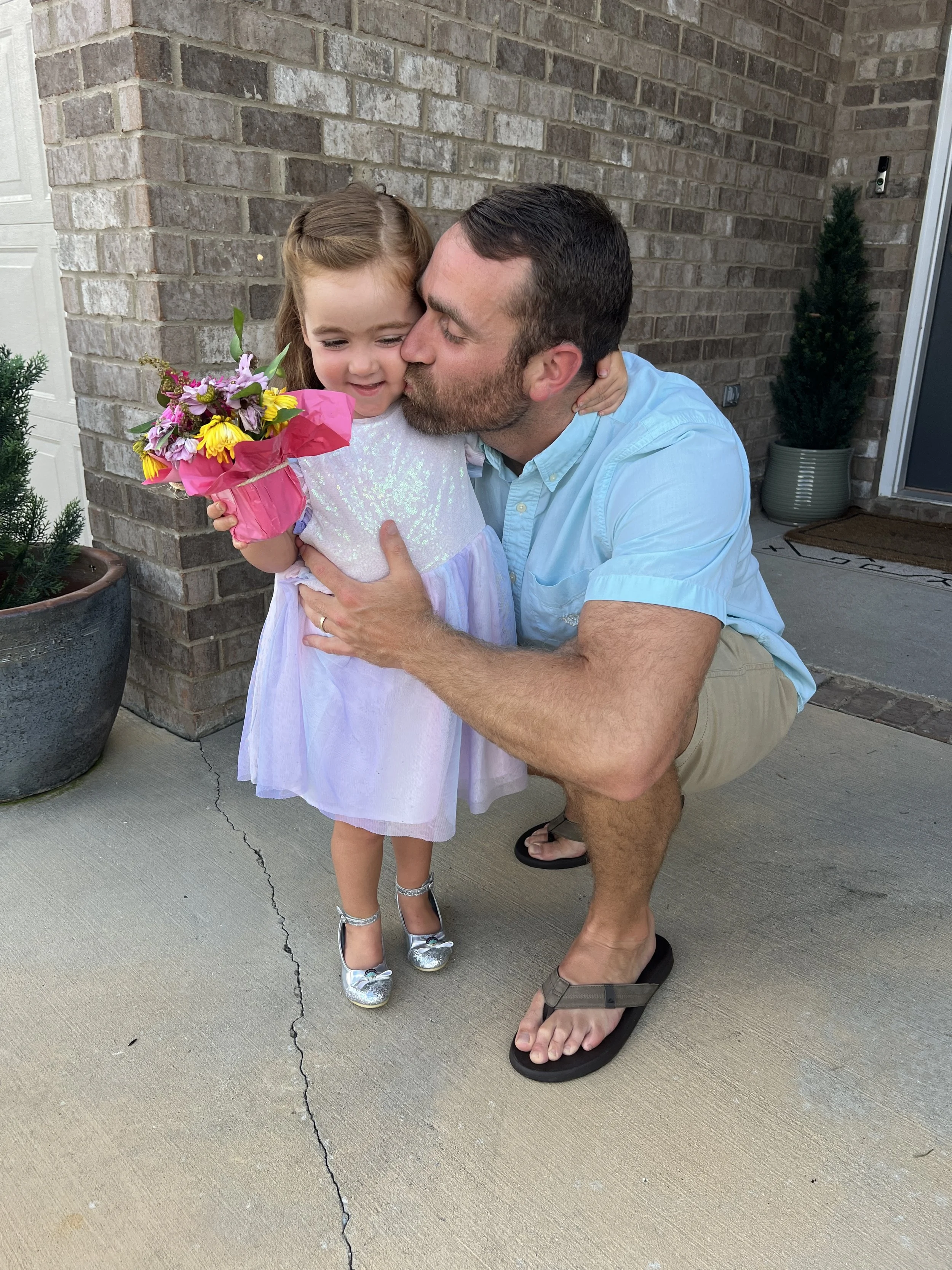 Dad kneeling with his daughter holding a bouquet