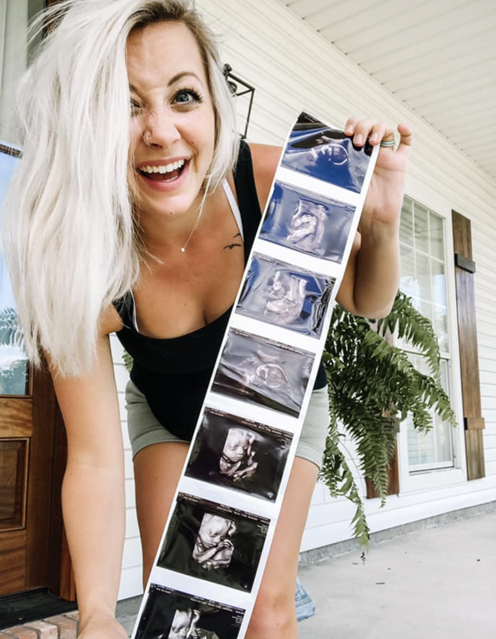 Mom smiling while holding a strip of ultrasound photos