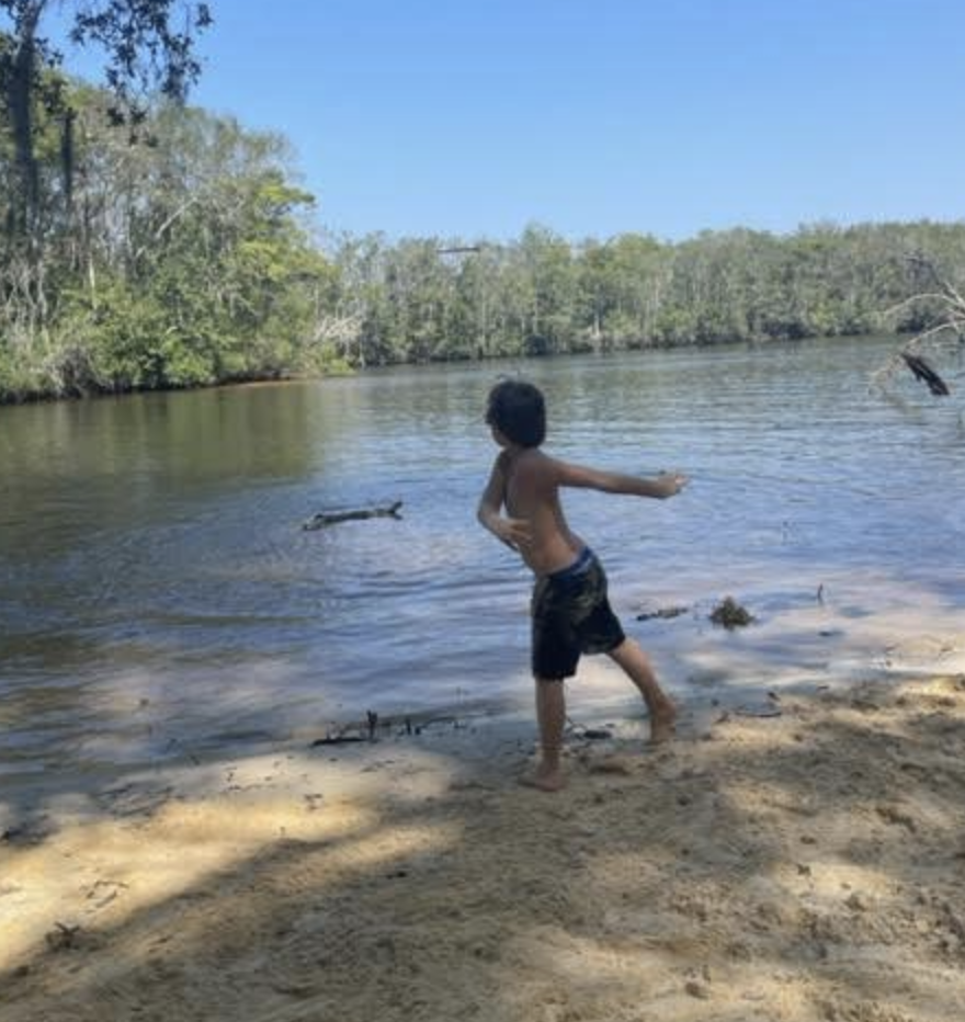 Child skipping rocks at the edge of a river