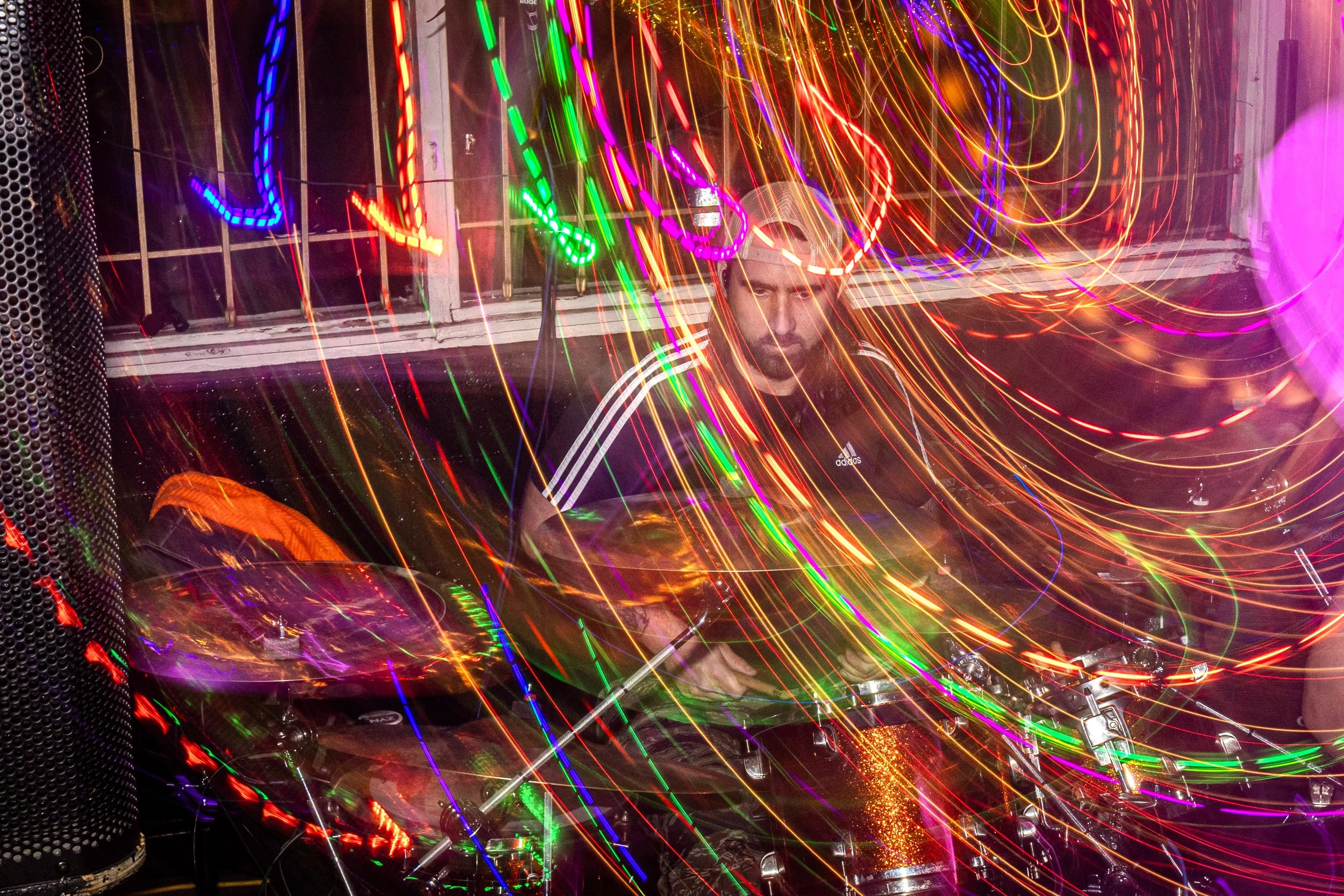 A DJ is performing at a nightclub with colorful light streaks and effects around him, creating a vibrant and energetic atmosphere.