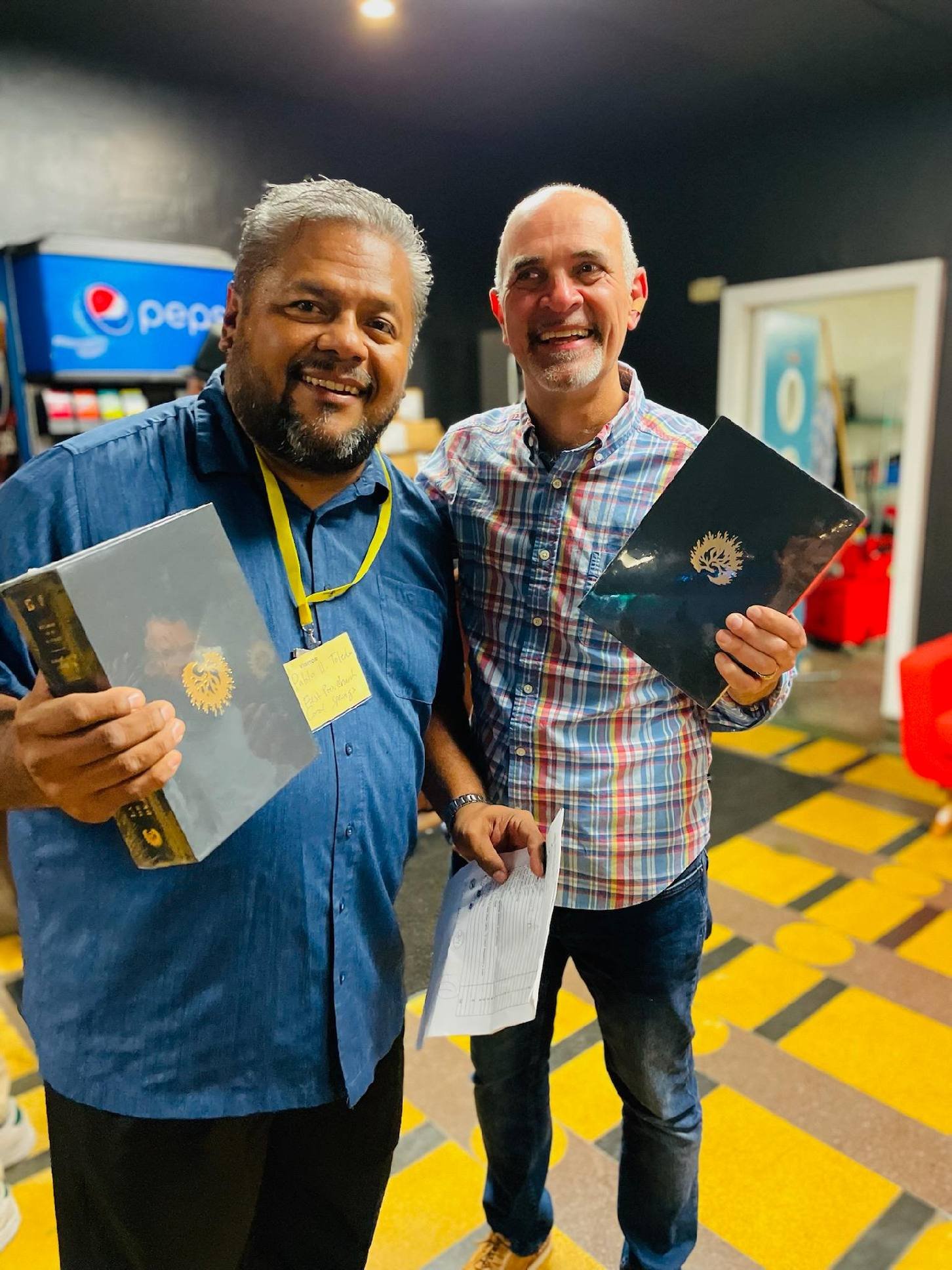 Two smiling men holding black award plaques at an indoor event.