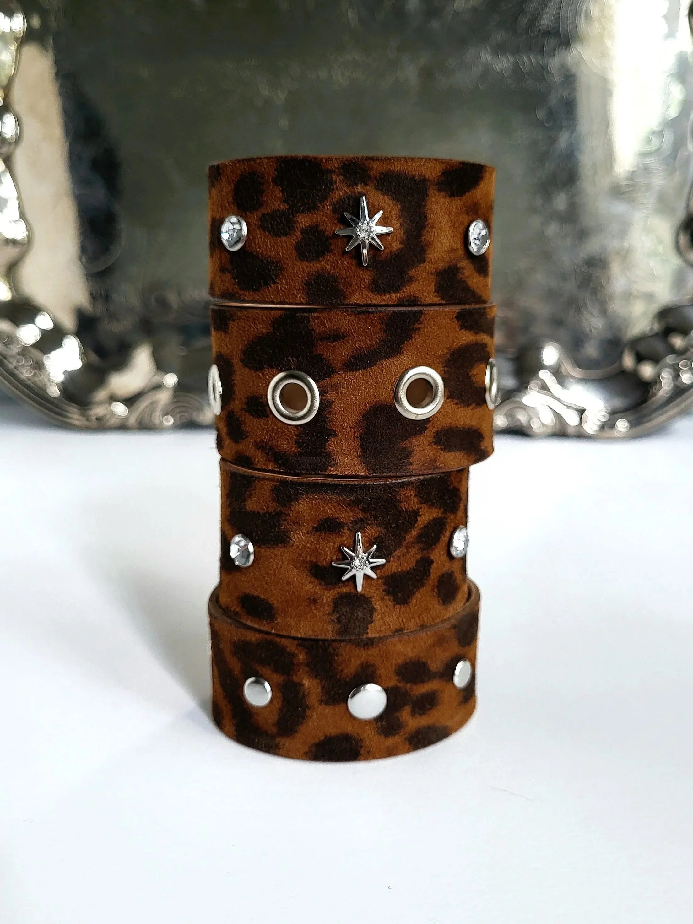 A brown leopard print leather bracelet with silver star and round stud embellishments.