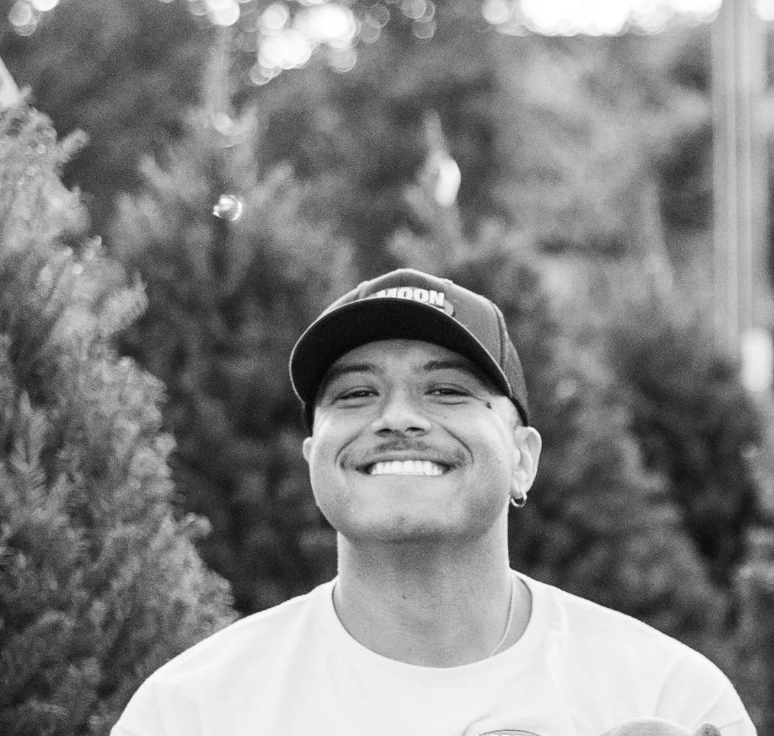 Smiling young man wearing a baseball cap and white T-shirt outdoors