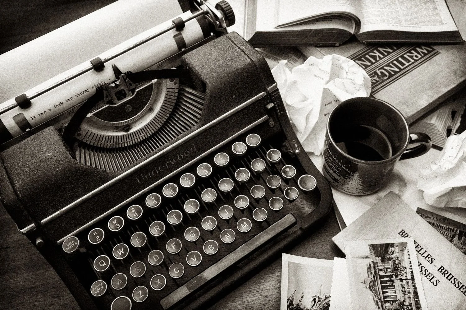 Vintage Underwood typewriter with paper, coffee mug, books, and scattered notes on a desk