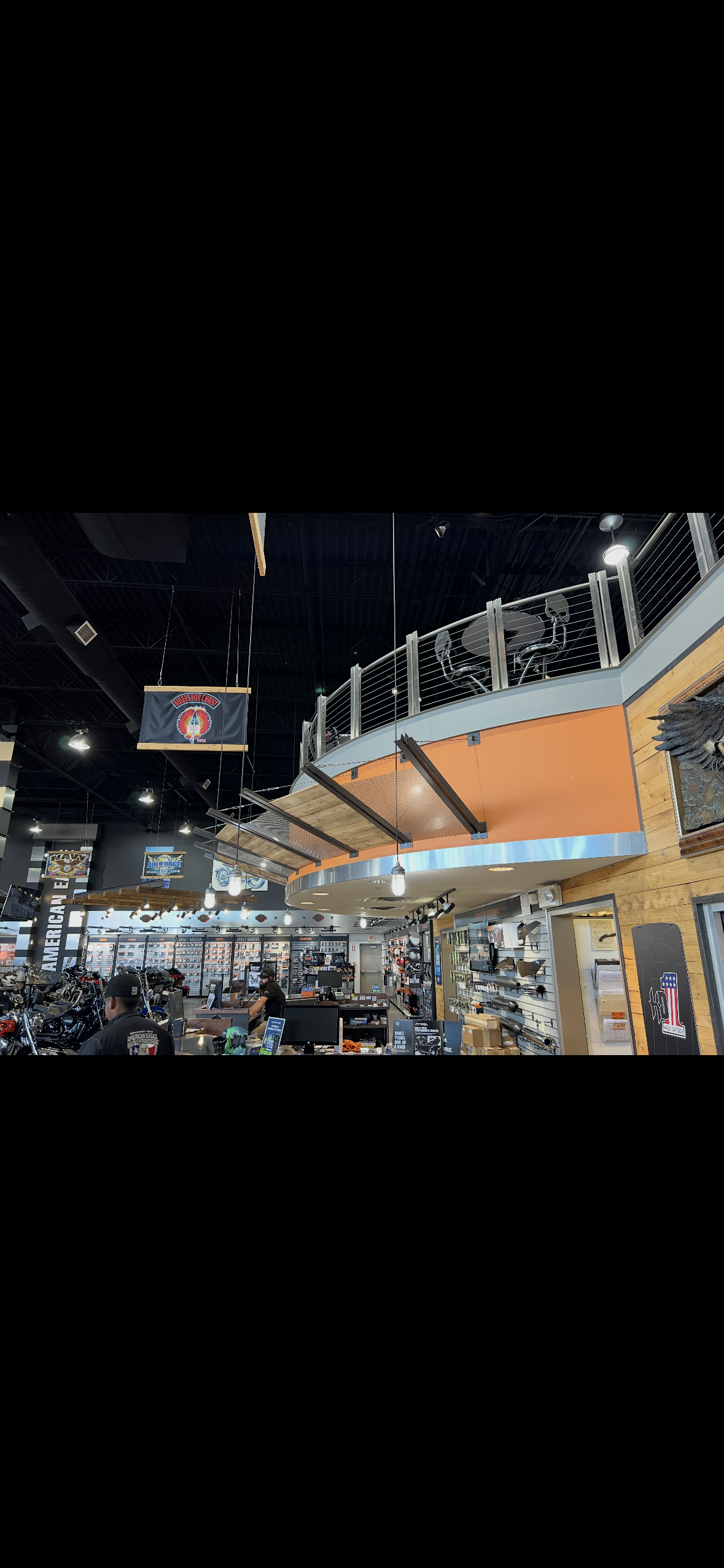 Interior of an American motorcycle dealership with motorcycles, parts displays, service counters, and branded hanging signs.