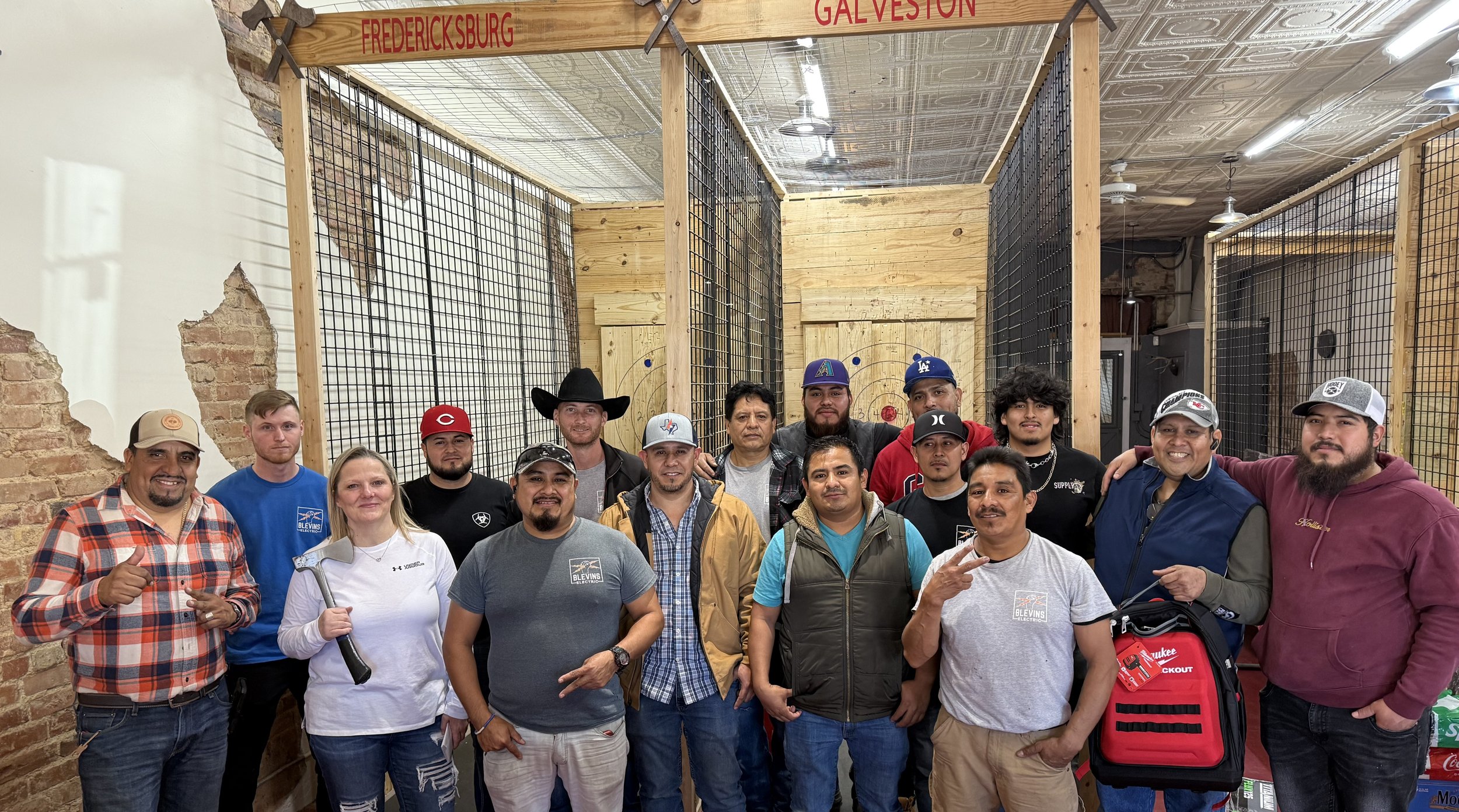 Group photo of employees posing in front of indoor axe-throwing lanes in Galveston, Texas