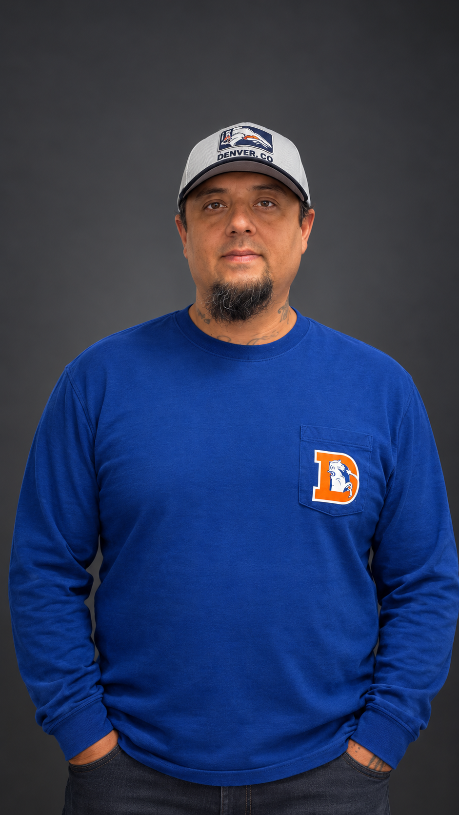 Man wearing a Denver Broncos cap and blue sweatshirt with a Broncos logo against a dark gray background