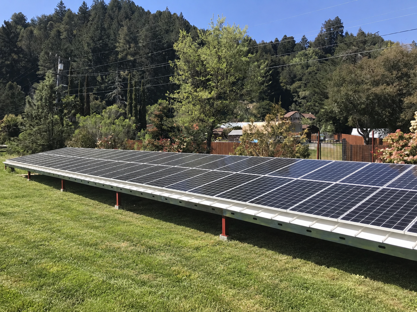 Ground-mounted solar array beside a neatly mowed lawn.