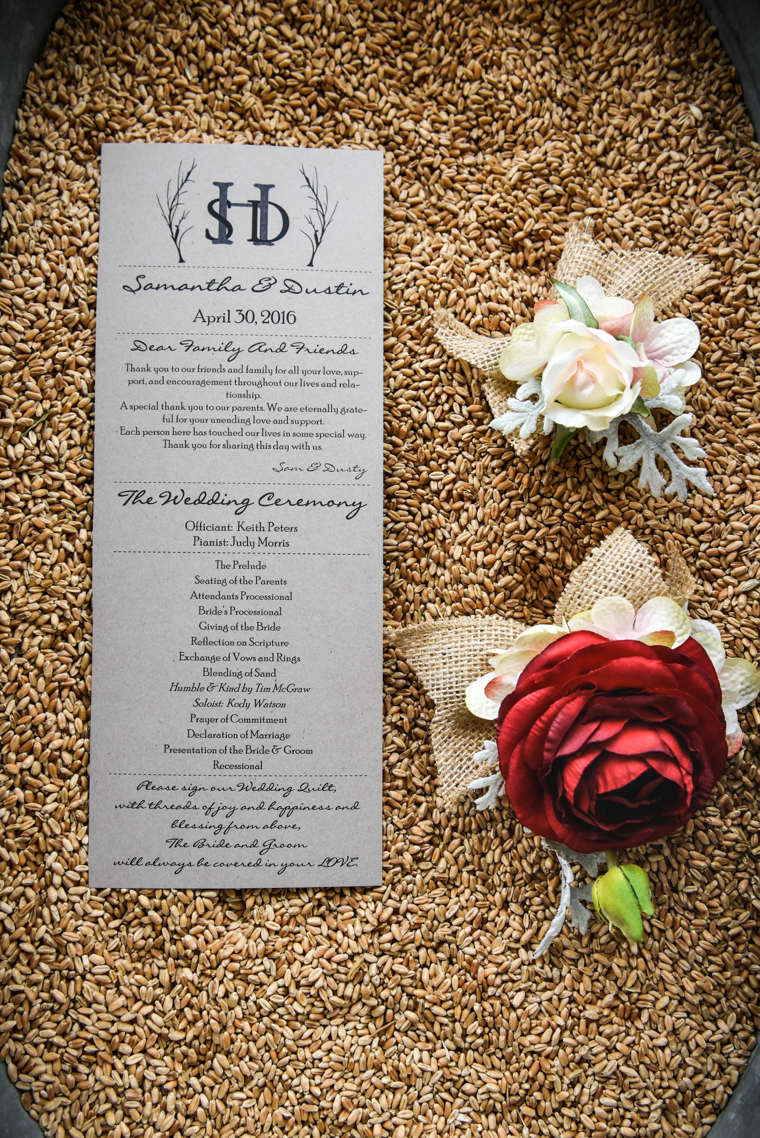 Wedding program card on top of a bed of wheat and decorated with flowers and burlap.