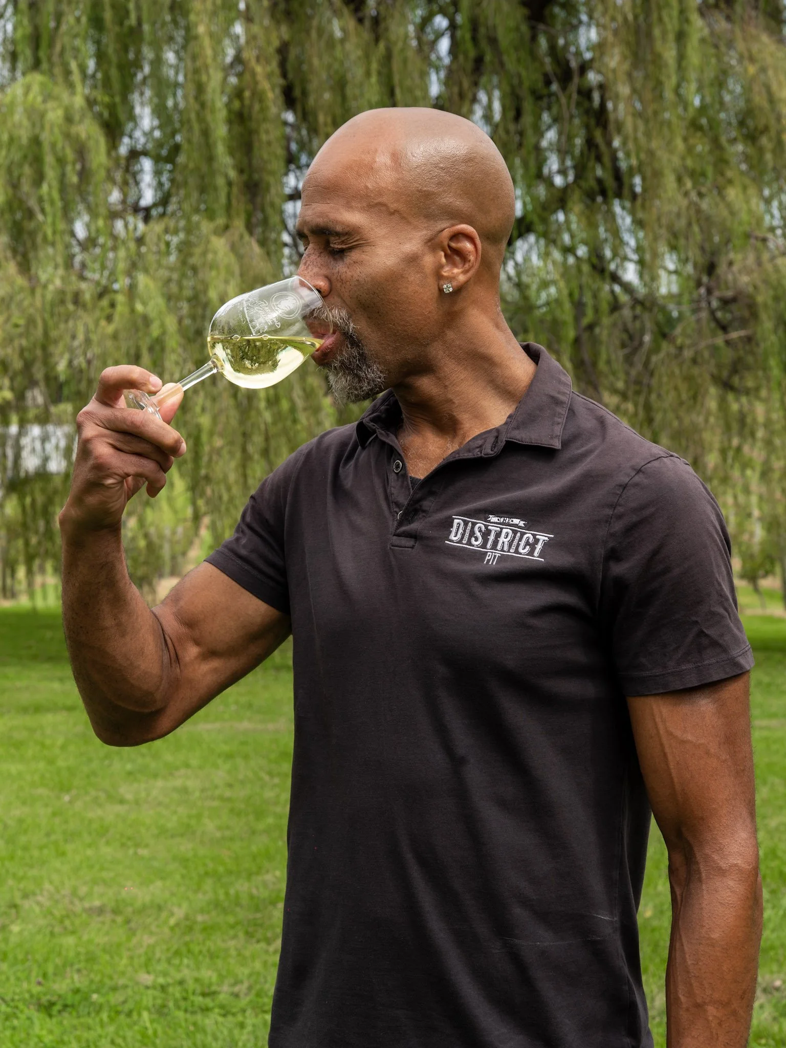 picture of roger drinking wine with a district pit shirt on