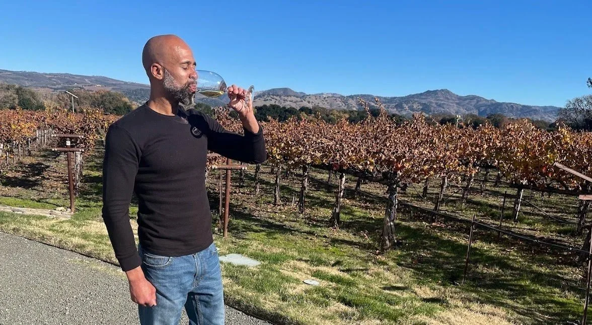 a picture of roger drinking wine in a vineyard