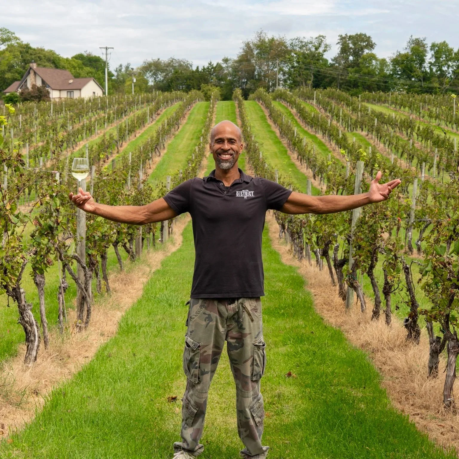 a picture of roger standing in a grape farm with his arms extended