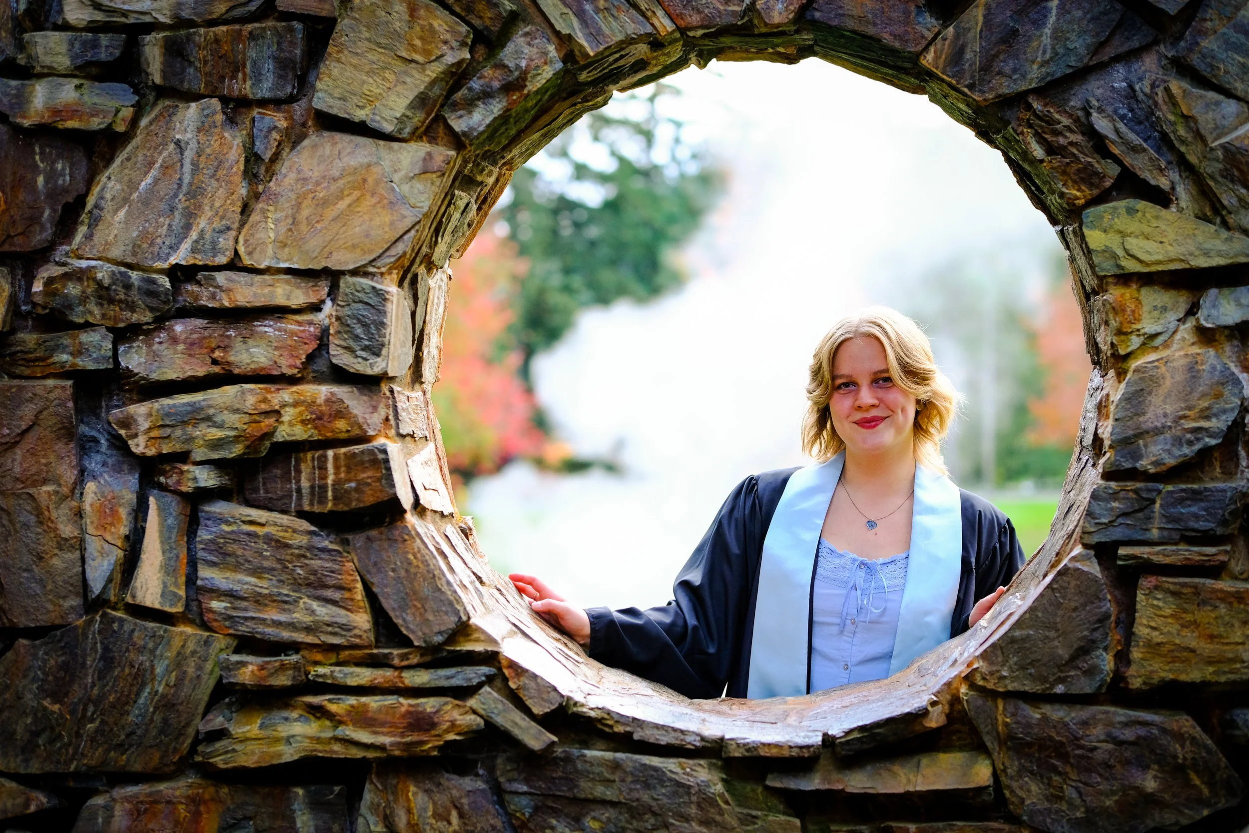 Blonde woman standing behind a stone archway outdoors
