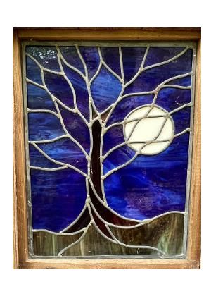 Stained glass window depicting a bare tree silhouetted against a deep blue night sky and full moon