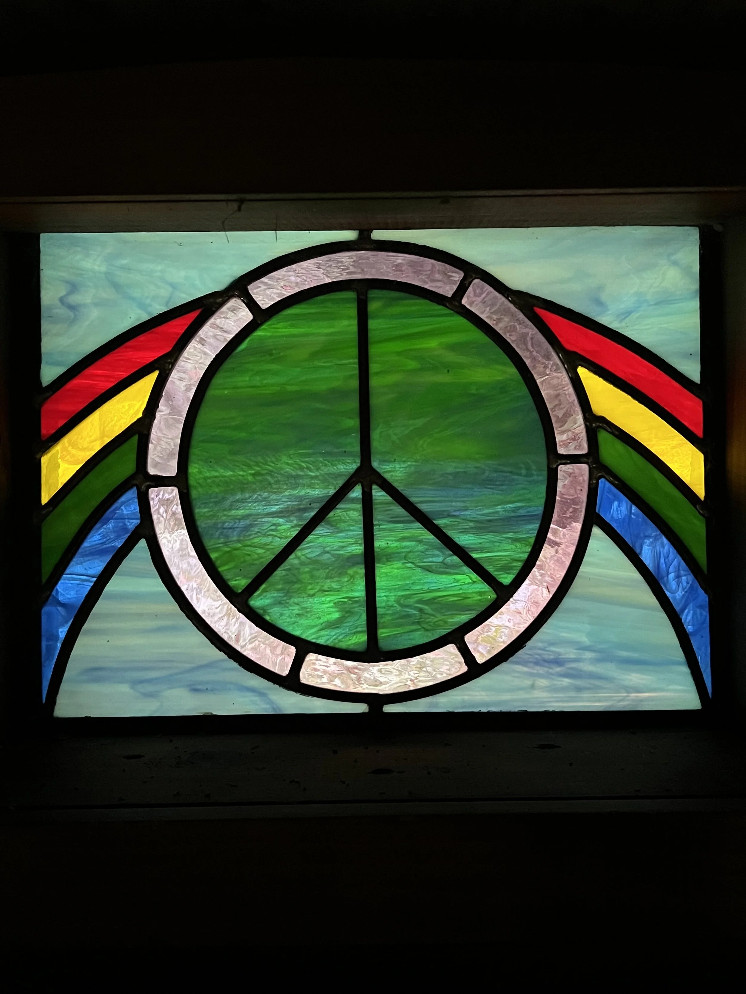 Colorful stained-glass window with a green circular center, pink border, and red, yellow, and blue geometric accents