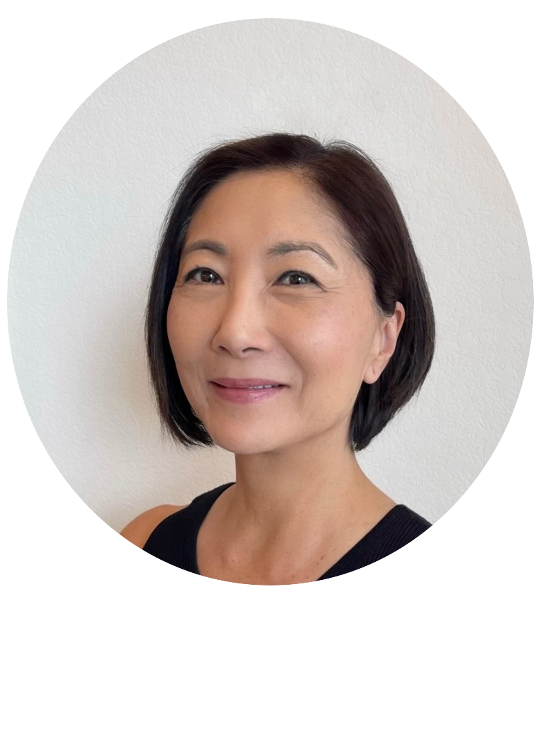 Portrait of a smiling middle-aged Asian woman with short dark hair wearing a black top against a white wall
