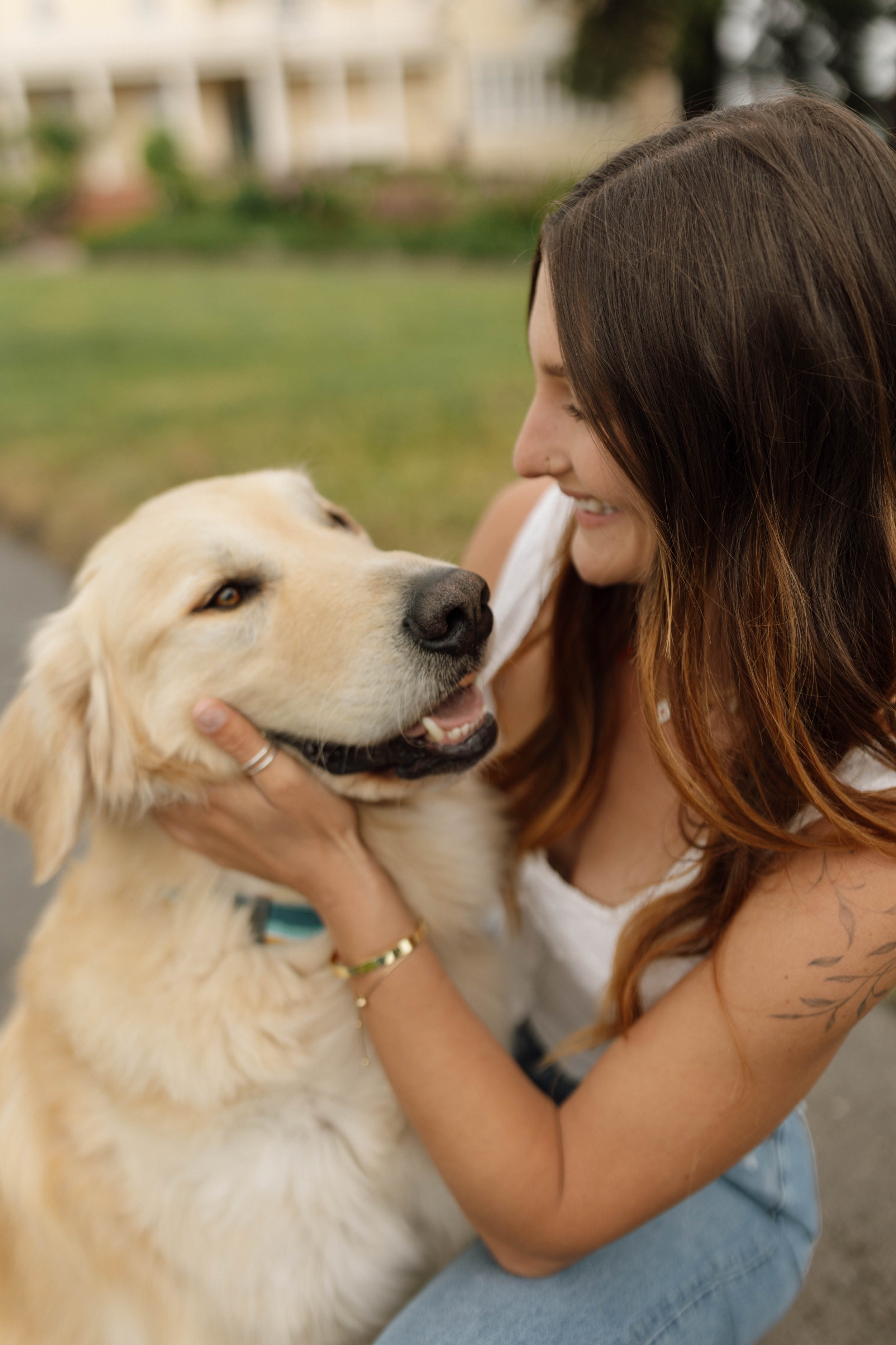 Woman smiling and holding a happy golden retriever outdoors