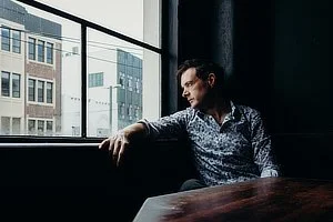 Man sitting by a large window in a city building