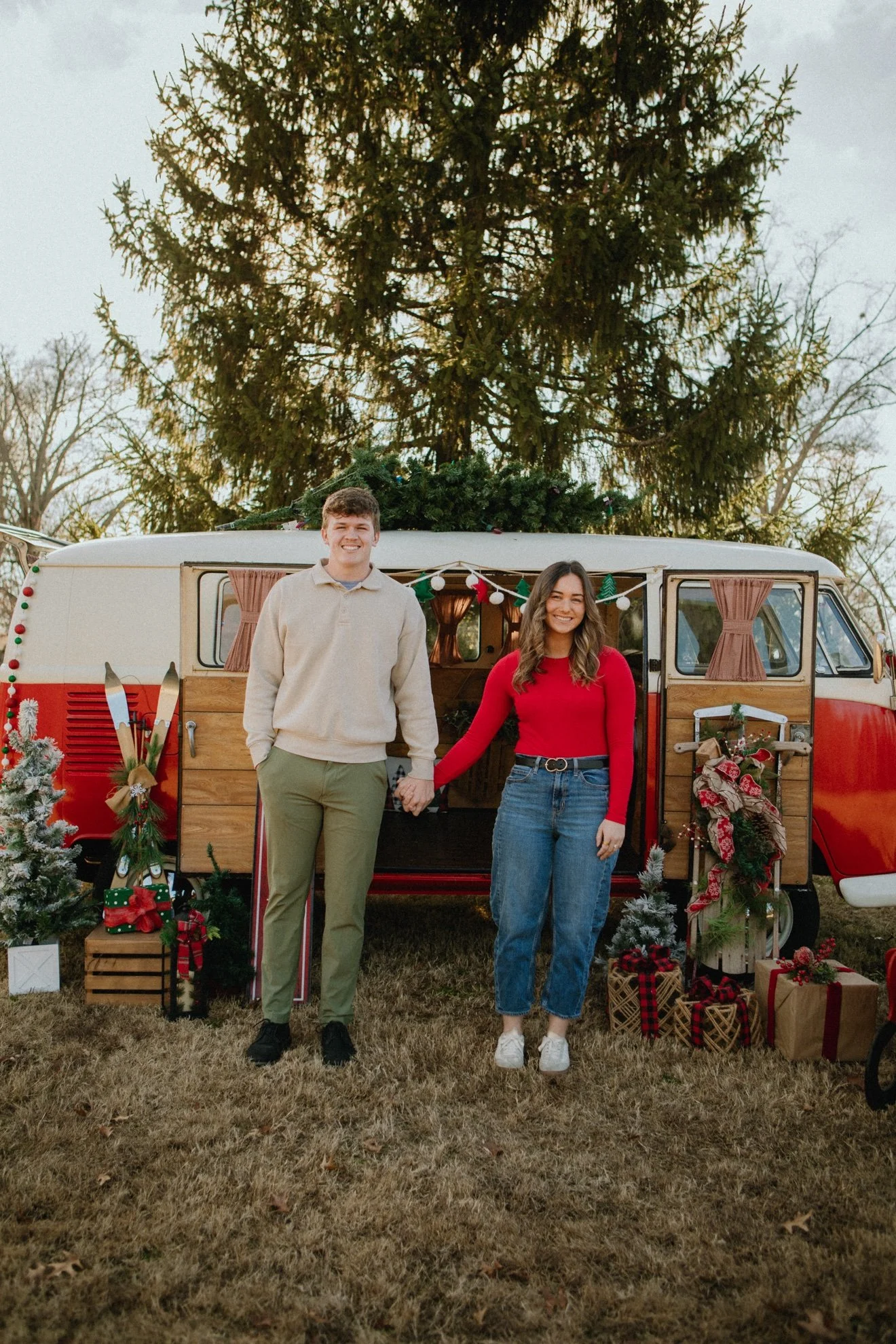 Couple with Ruby, red VW bus decorated for Christmas, side view