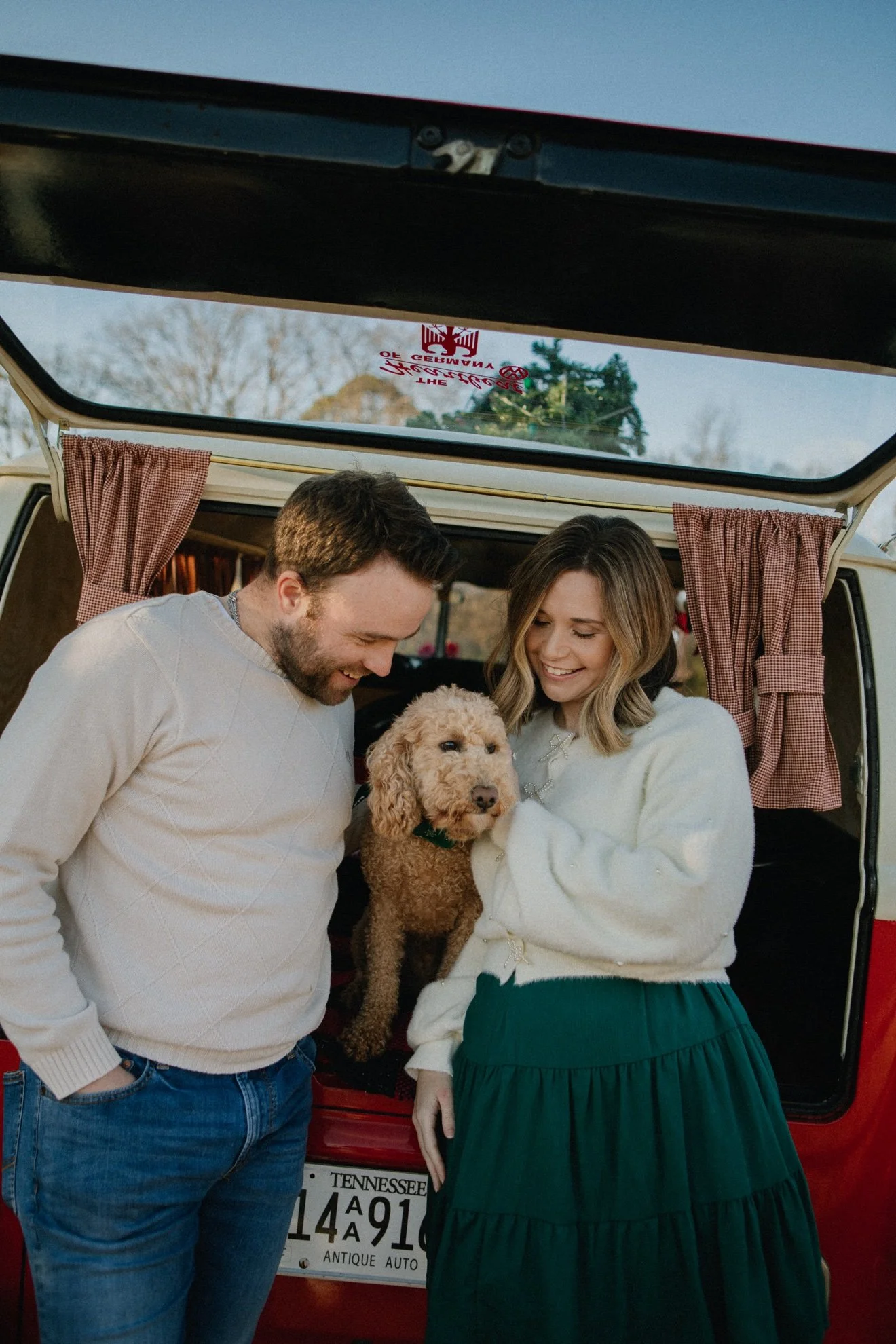 Couple with dog at the back of Ruby, red VW bus decorated for Christmas