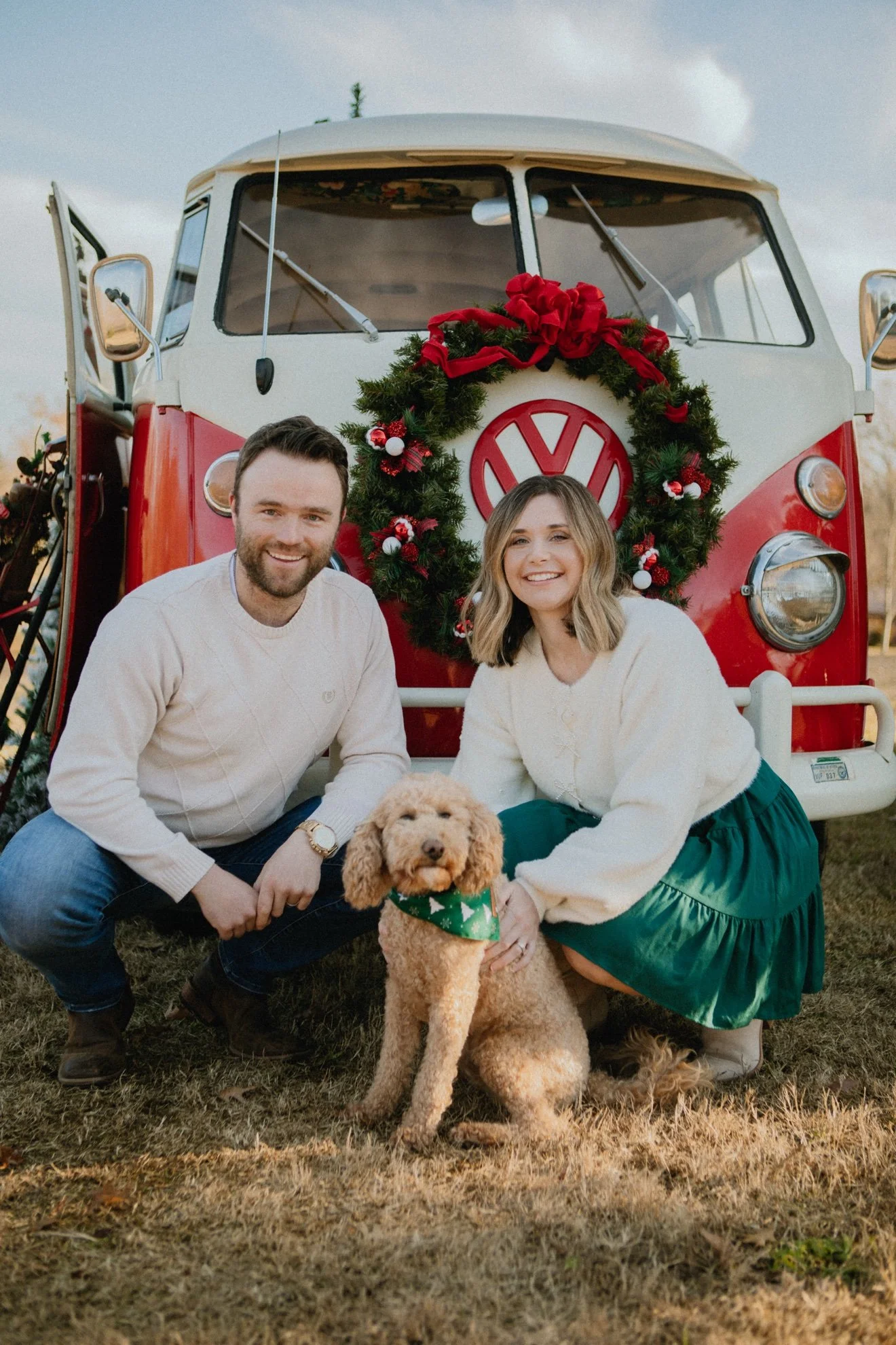 Couple with dog and Ruby, red VW bus with Christmas wreath, front view