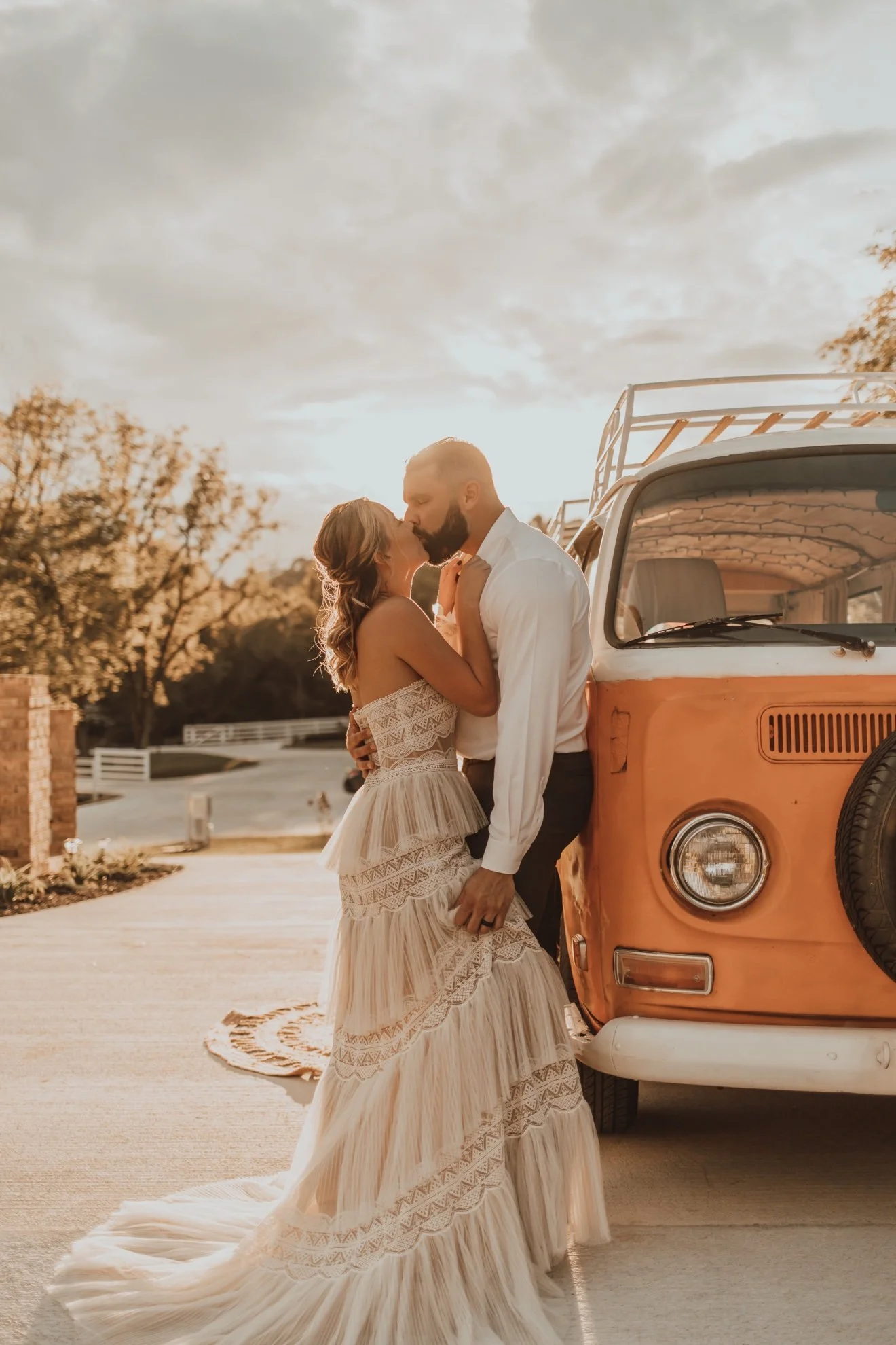 Wedding couple kissing in front of Nancy at golden hour, orange VW bus