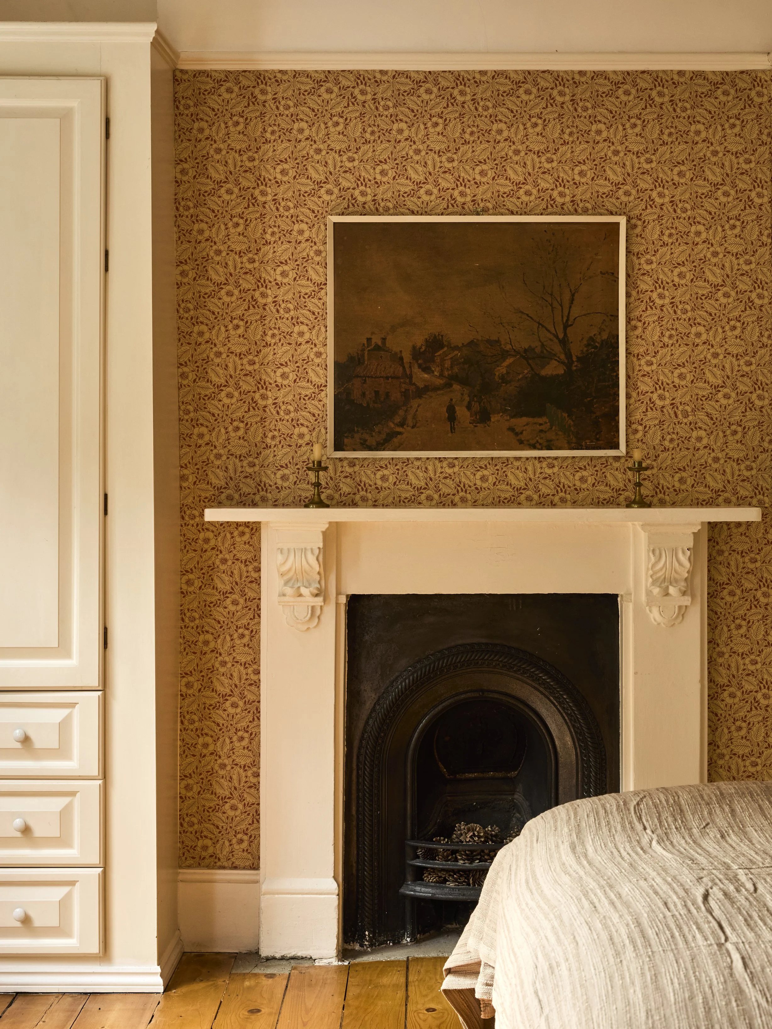 A cosy living room corner in Stoke Newington with a fireplace, framed artwork, and a textured beige throw.