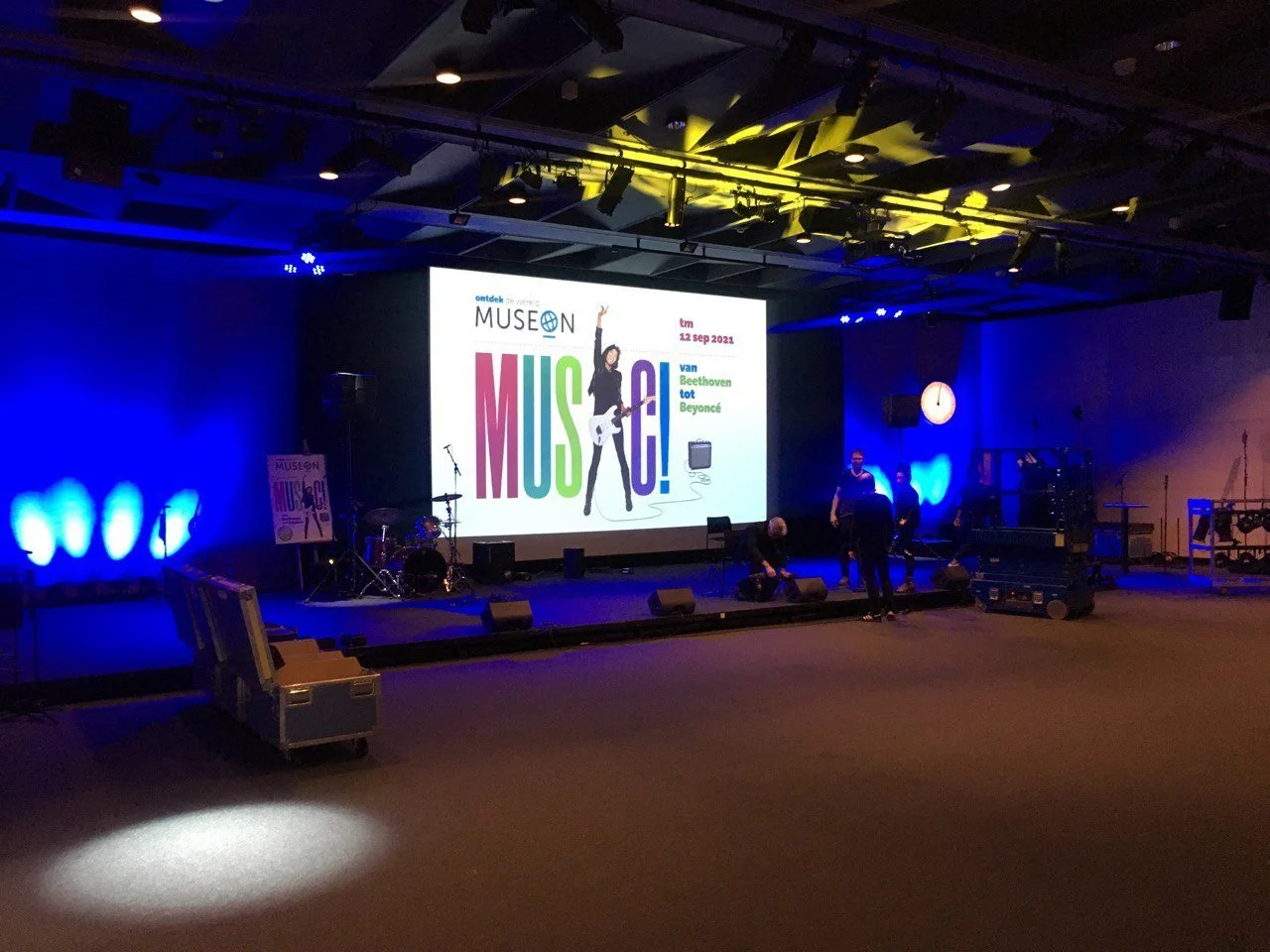 Podium met muziekinstrumenten en groot scherm met aankondiging van Museon-expositie ‘MUSIC!’