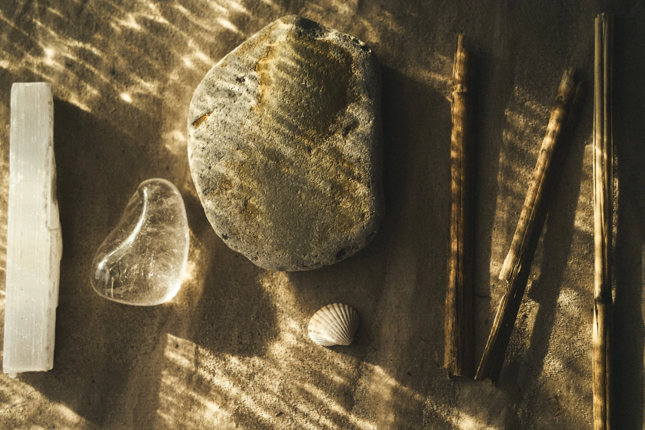 Large weathered stone sphere displayed with clear glass and seashells in a dimly lit exhibit