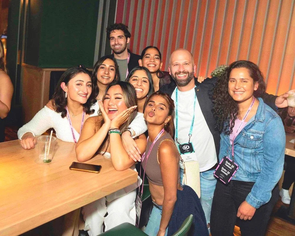 Group of smiling friends posing together at an indoor event around a wooden table