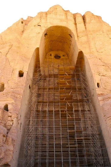The monumental niche of the Great Buddha of Bamyan, carved into the sandstone cliffs centuries ago. Scaffolding inside the empty niche reflects ongoing conservation work at this UNESCO World Heritage Site, where the remains of the Buddhas bear witnes