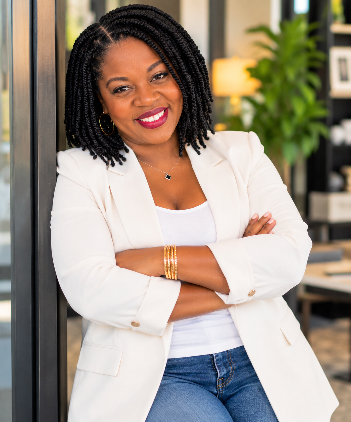 Nakisha Hicks smiling in a white blazer with her arms crossed.