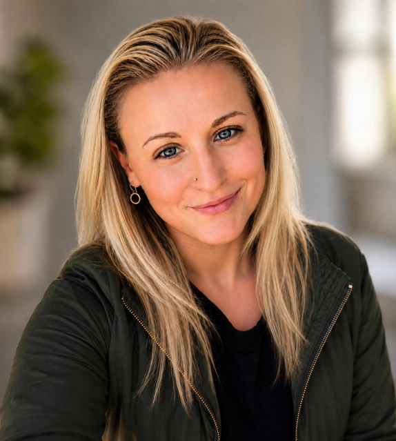 Portrait of a smiling blonde woman wearing a dark jacket and gold hoop earrings