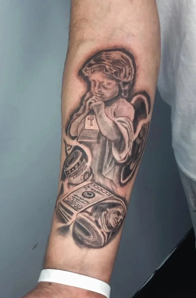 Black-and-grey praying angel and money forearm tattoo by Bladi at Apex Arts Collective, completed as a walk-in.