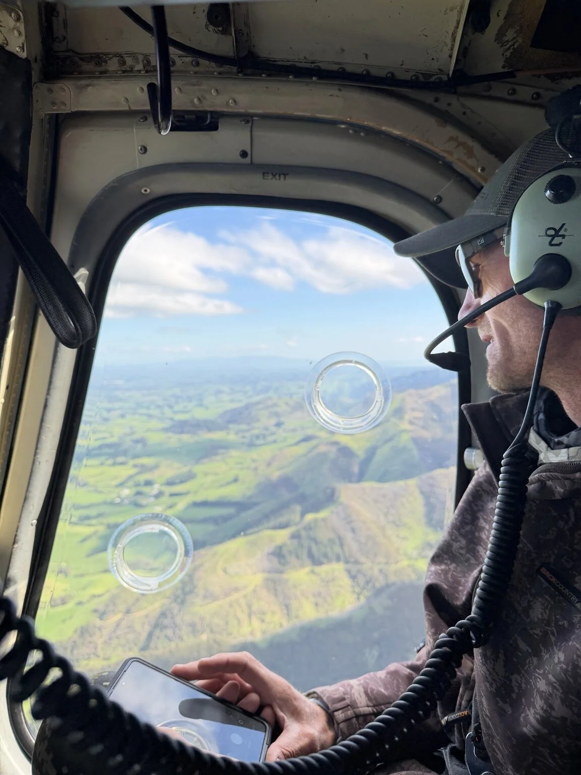 Ben Ellison in a helicopter overlooking the New Zealand countryside.
