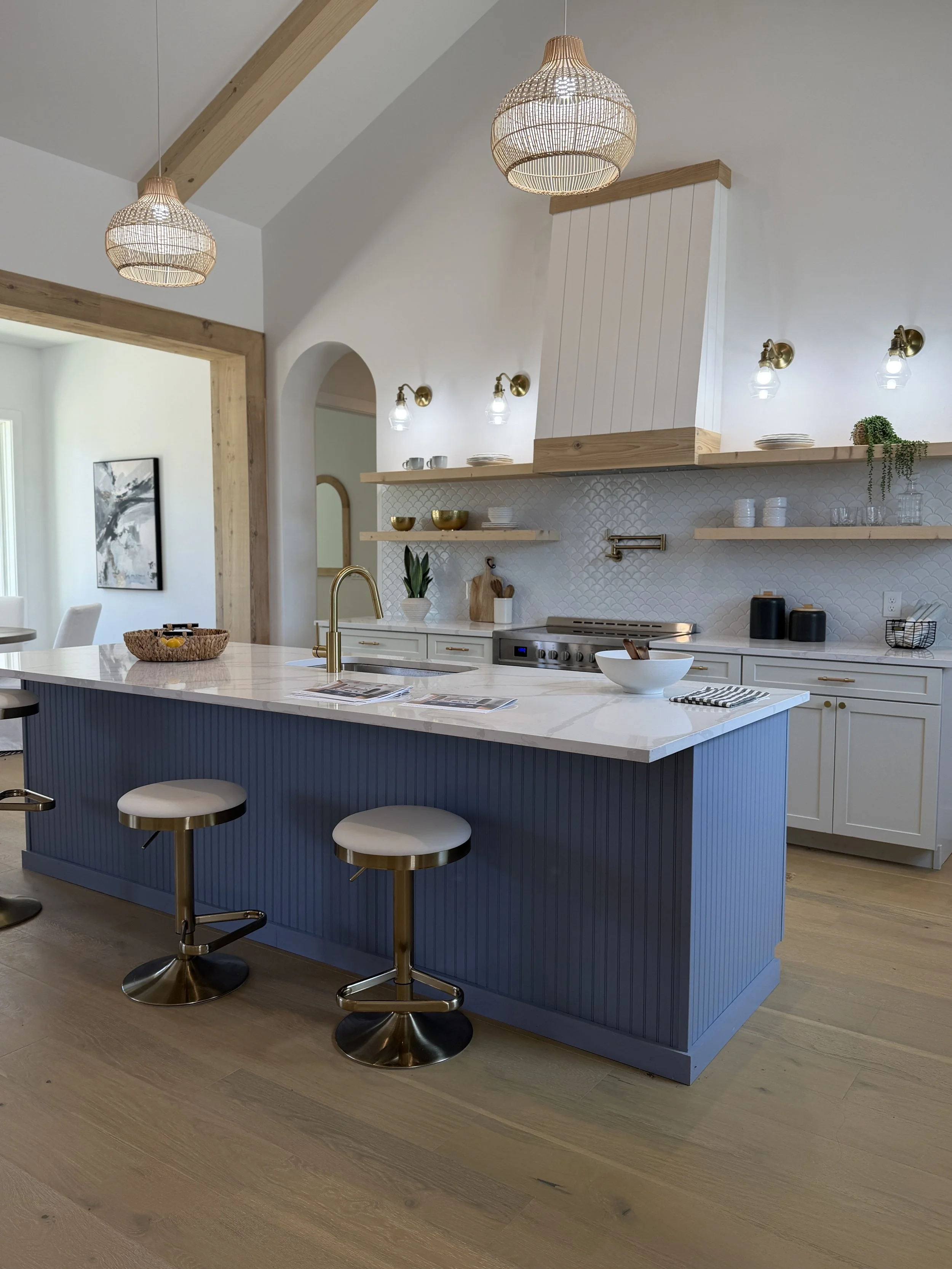 Bright kitchen with a blue island and wood beams in a Hill Country home