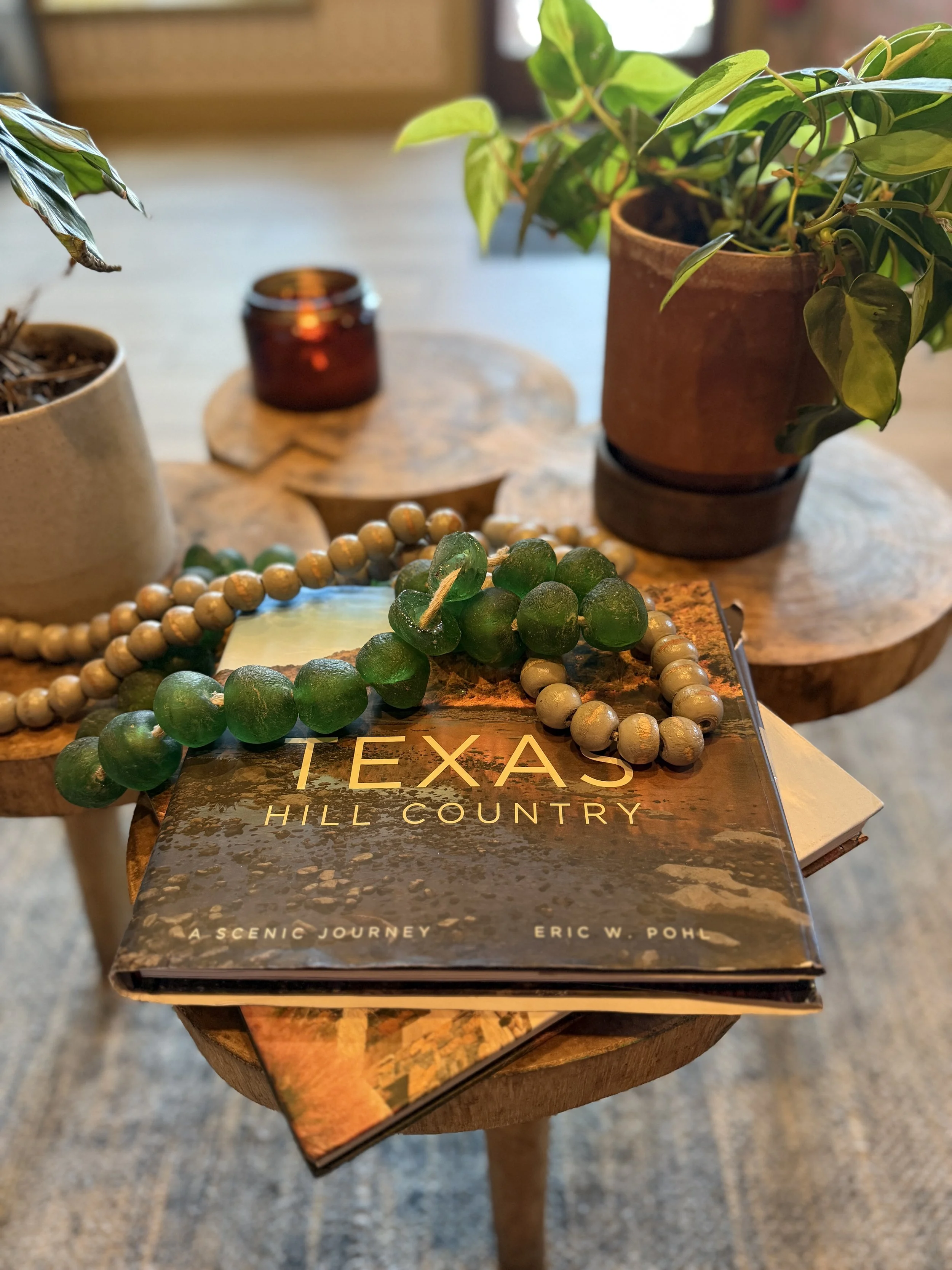 Coffee table styled with a Texas Hill Country book, wood beads, and greenery
