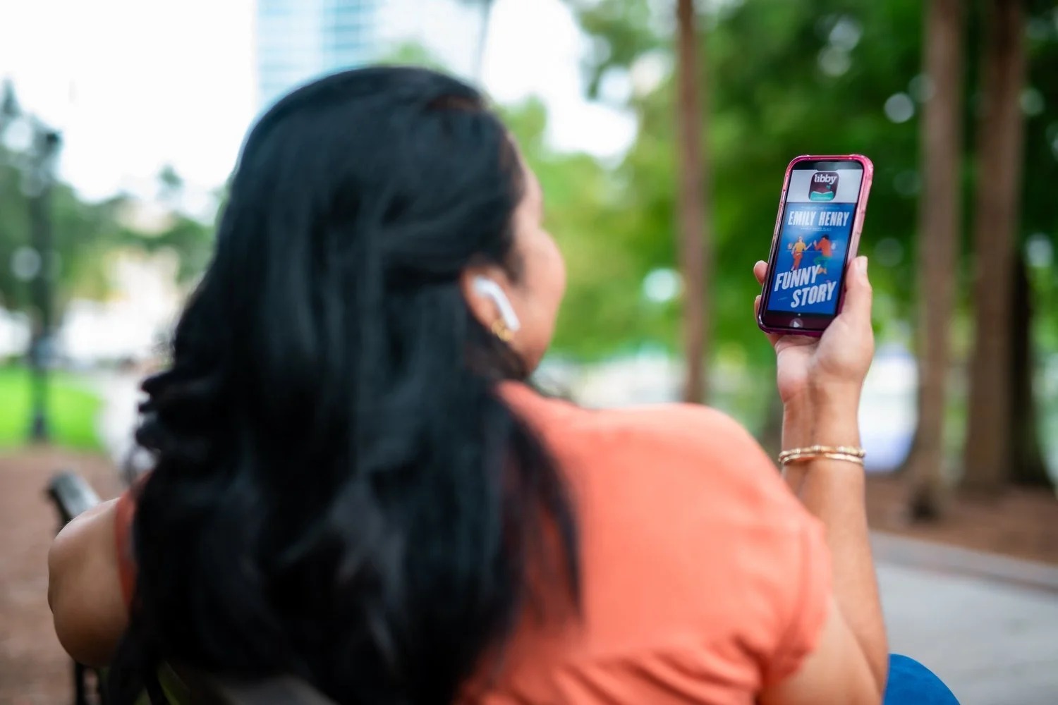 Woman listening to a free library audiobook on her phone outdoors