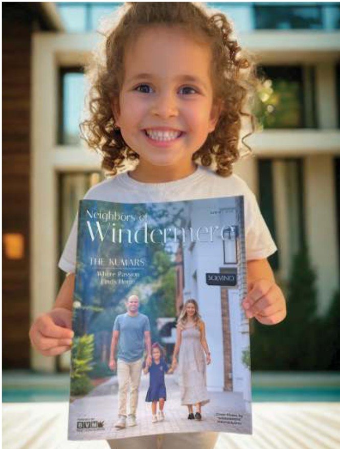 Young reader Solia smiling as she holds her family's Windermere magazine feature