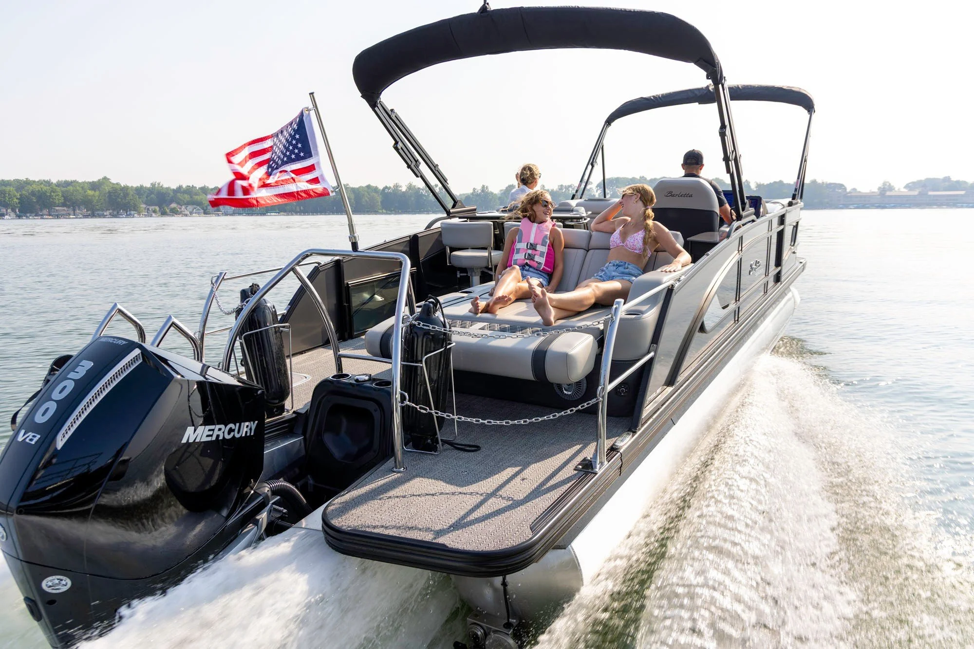 Family boating on the lake with an American flag flying, Action Water Sports