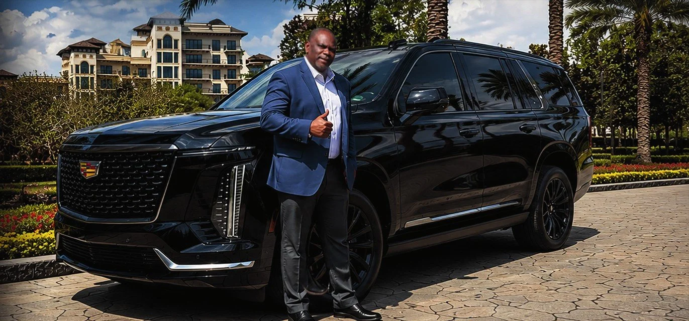 Serge, owner of Olive Luxury Ride, gives a thumbs up beside his black Cadillac Escalade in Windermere