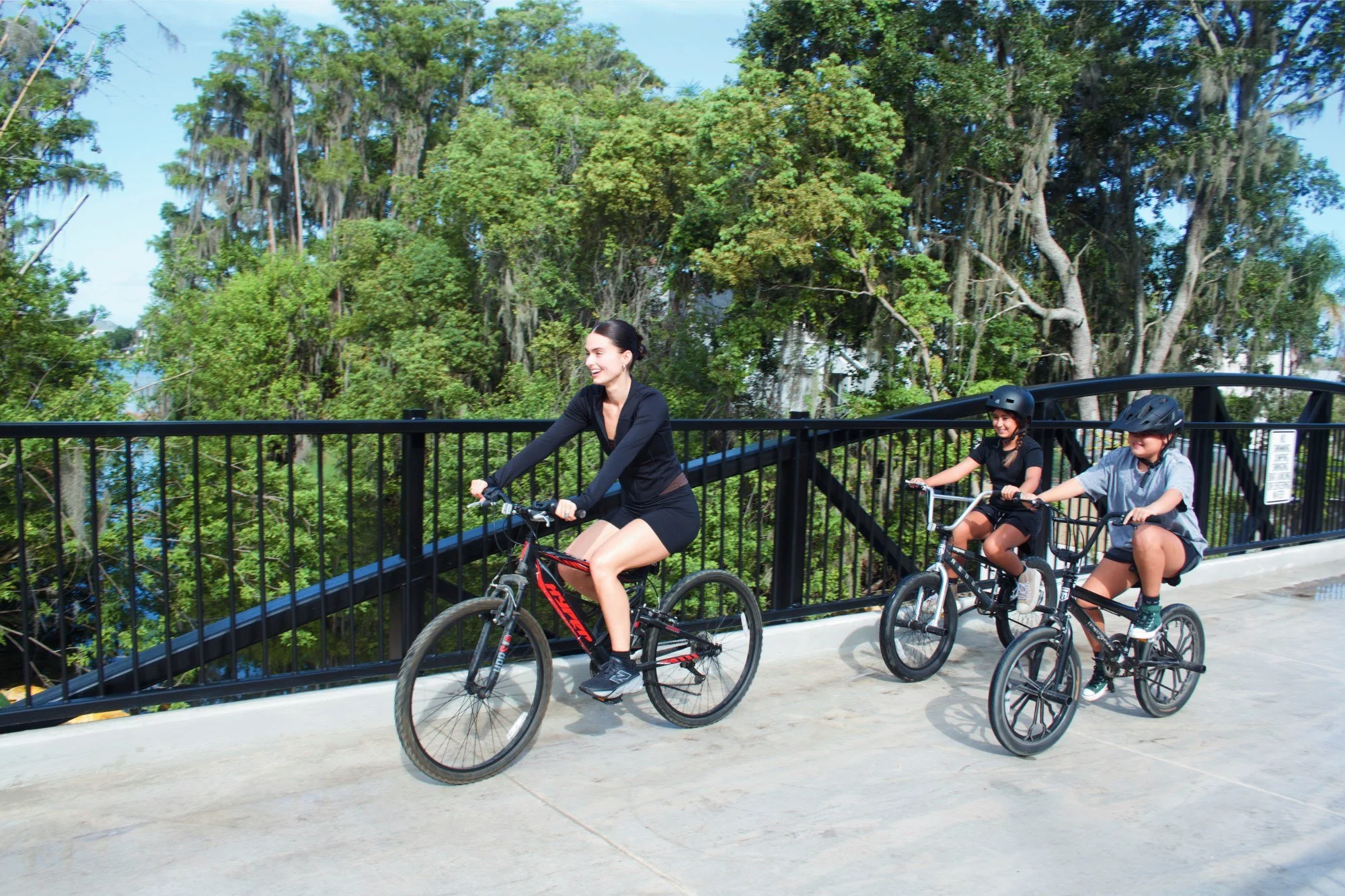 Children riding bikes across the new Ward Trail bowstring bridge in Windermere