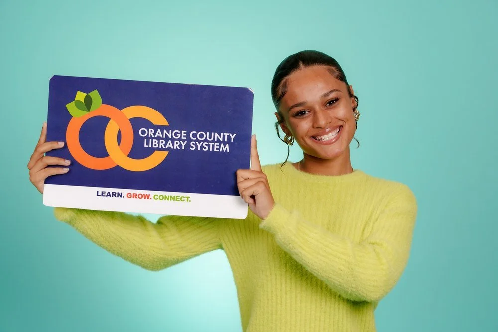 Young woman holding an Orange County Library System library card