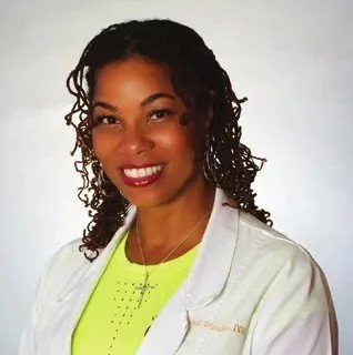 Dr. Wendi Wardlaw, owner of Wholistic Dental Center, smiling in a white coat
