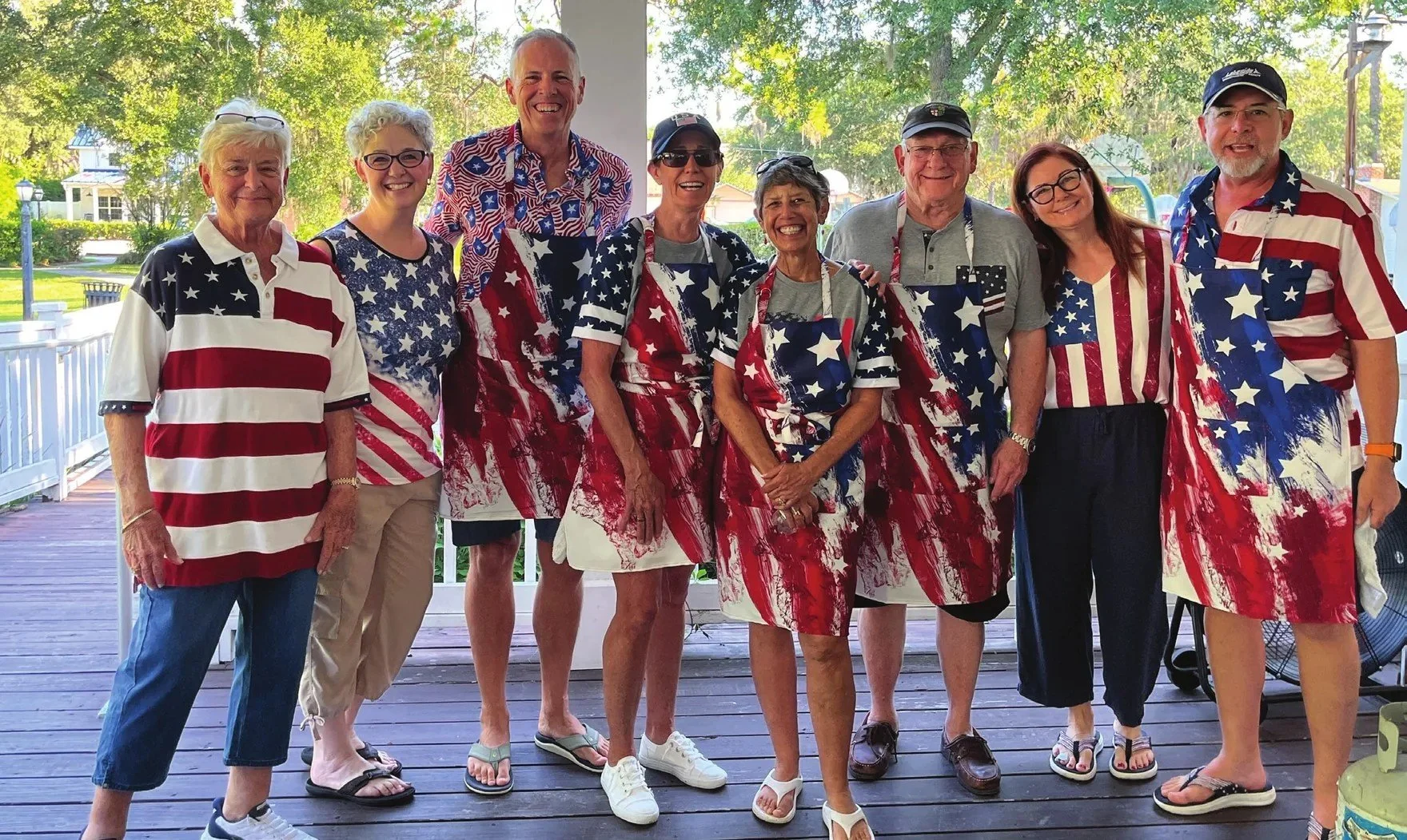 Eight people in matching American flag shirts standing together on a porch
