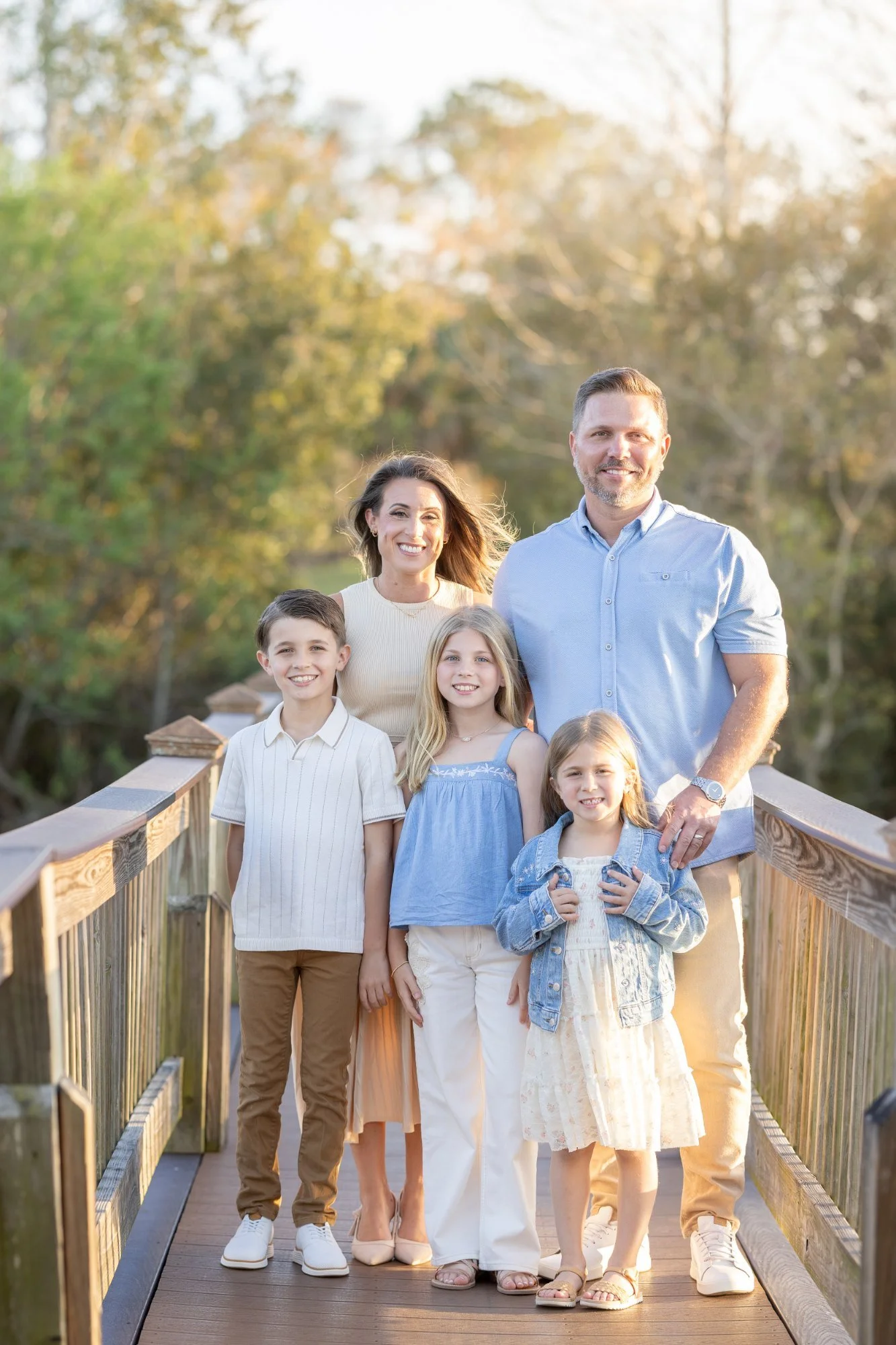 Joe and Amanda Ferst with their three children on a wooden bridge