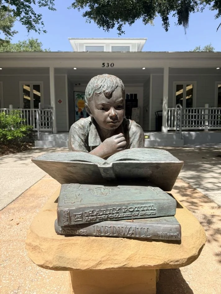 Summertime Read bronze sculpture of a boy reading outside the Windermere library